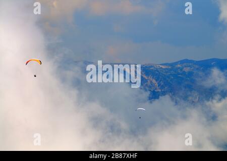 Extreme Erholung, Fallschirmspringer fliegt über die Berge und Felsen. Weiße Wolken am Himmel Stockfoto