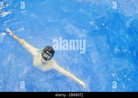 Der Mensch in einer Unterwassermaske tritt aus dem Wasser hervor, im Urlaub taucht er im Ozean. Stockfoto