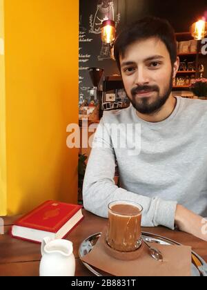 Junger Mann, der in einem Café Interior sitzt und seine Getränke genießt Stockfoto