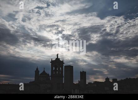 Dramatischer Himmel mit dunklen Wolken über den Oberstadttürmen von Bergamo und den Kuppeln der Kirche. Die Region Lombardei in Norditalien wurde zu einem Epizentrum viraler Pandemie Stockfoto