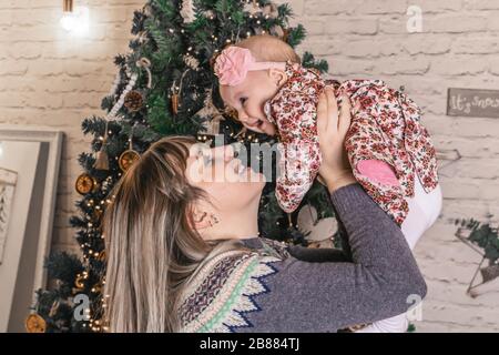 Fröhliche junge Mutter mit ihrem süßen Baby auf dem weihnachtsfoto Stockfoto