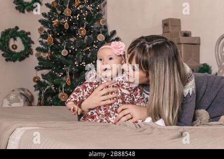 Fröhliche junge Mutter mit ihrem süßen Baby auf dem weihnachtsfoto Stockfoto