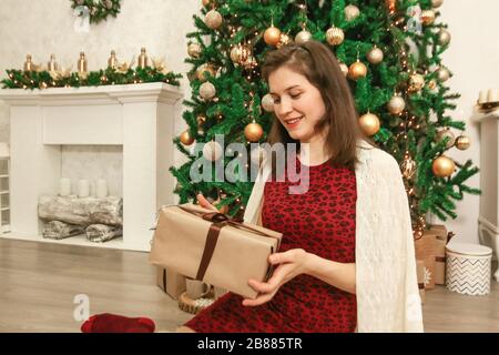 Glückliches Mädchen öffnet Weihnachten präsentiert zu Hause Foto Stockfoto
