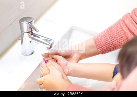 Mutter hilft ihrem Kind in der Hand waschen mit Seife unter fließendem Leitungswasser Stockfoto