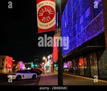 Autos werden entlang der Broadway Avenue, auch bekannt als Automobile Alley, geparkt, da festliche Feiertagslichter Geschäftsgebäude drapieren. Stockfoto