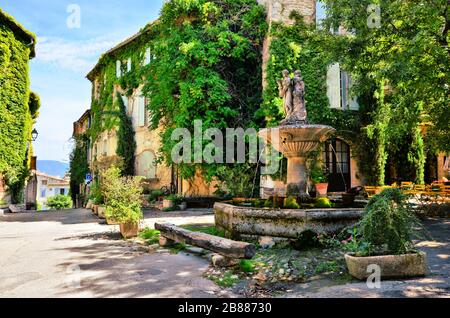 Belaubter Stadtplatz mit Springbrunnen in einem malerischen Dorf in der Provence, Frankreich Stockfoto