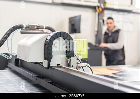 Der Techniker der Druckerei arbeitet an einer großen CNC-Computer- numerischen Steuerungs- und Schneidemaschine Stockfoto