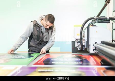 Der Techniker der Druckerei arbeitet an einer großen CNC-Computer- numerischen Steuerungs- und Schneidemaschine Stockfoto