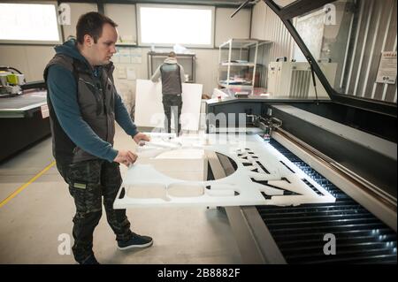 Der Techniker der Druckerei arbeitet an der Laser-CNC-Computer-numerischen Steuerungs- und Schneidemaschine Stockfoto