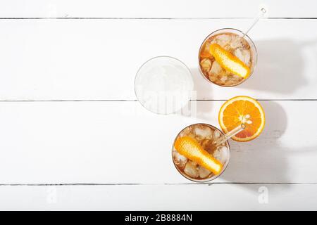 Kaffeemocktail aus kaltem Brühen mit Orangenschale und Strohhalm. Glas mit Espresso-Tonika aus Zitrusfrüchten und Eis auf weißem Hintergrund. Flacher Lay. Erfrischender Sommer Stockfoto