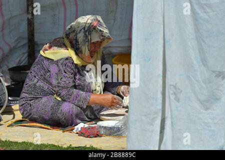 TURKMENISTAN, ASHGABAT - 1. MAI 2019: Tag des turkmenischen Rennpferdes. Öffentlich. Frau, die in einem Festzelt sitzt. Stockfoto