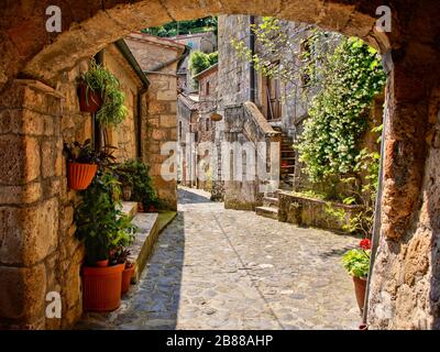 Gepflasterte Straße mit Bogen in einem toskanischen Dorf, Italien Stockfoto