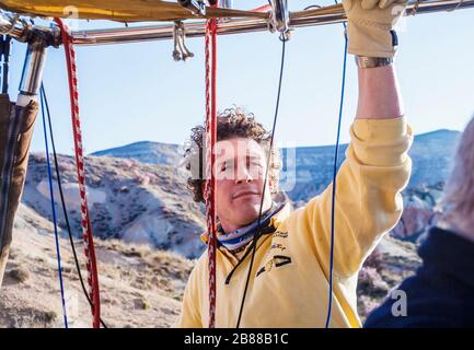 Junger männlicher Pilot in einem frühen Morgen Kapadokya Luftballons Heißluftballonflug über der märchenhaften Kaminlandschaft von Gorome, Kappadokien, Türkei Stockfoto