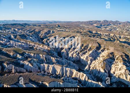 Panorama-Luftbild am frühen Morgen über die dramatische, aride, erodierte Feenkornsteinlandschaft von Gorome, Kappadokien, Türkei mit einem ausgetrockneten Flusstal Stockfoto