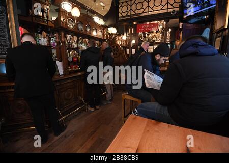 Kunden im Red Lion Pub in Westminster in London sehen sich das Fernsehen an, während Boris Johnson Pubs und Restaurants im ganzen Land bestellt, um heute Abend zu schließen, da die Regierung beispiellose Maßnahmen zur Deckung des Lohns von Arbeitern ankündigte, die ansonsten aufgrund des Ausbruchs des Coronavirus ihren Arbeitsplatz verlieren würden. Stockfoto