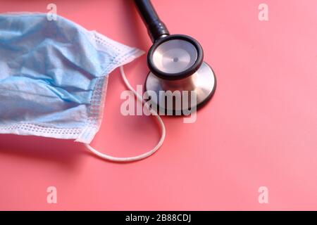 Nahaufnahme von Gesichtsmaske und Stethoskop auf pinkfarbenem Hintergrund Stockfoto