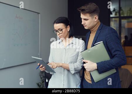 Geschäftsfrau mit Tablet pc diskutiert Online-Arbeit mit ihrem Kollegen im Büro Stockfoto