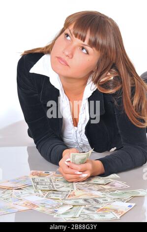 Porträt einer hübschen kaukasischen weißen brünette Frau, die in der Nähe von Euro- und Dollarscheinen liegt. Isoliert auf weißem Hintergrund Stockfoto