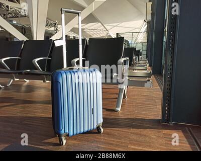 Blauer Koffer in einem leeren Flughafen. Wartebereich Flugverzögerung Stornierung. Reise- und Urlaubskonzept. Coronavirus COVID19 Quarantäne Stockfoto