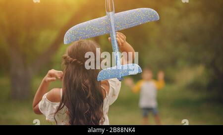Ein hübsches Mädchen und EIN kleiner Junge, der mit EINEM Spielzeugflugzeug spielt Stockfoto