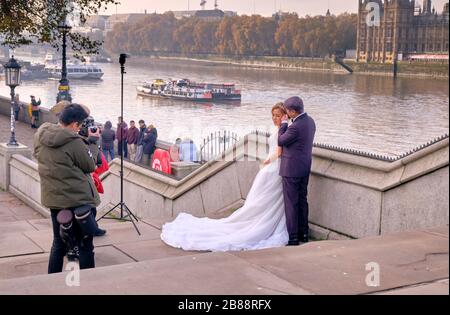 Hochzeitsfotograf, der ein Bild von einem Paar entlang der Themse in London aufgenommen hat Stockfoto