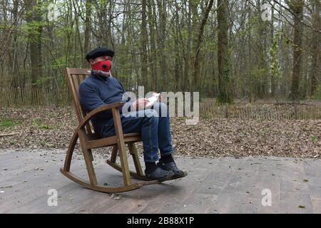 Mann im ländlichen Frankreich sitzt in Schaukelstuhl während der Covid 19 Virus-Pandemie. Abgeschiedene Abgeschiedenheit Isolation Versteck ländlichen Rückzug Stockfoto