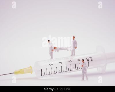 Miniatur Ärzte mit Patienten, die auf Spritze laufen Stockfoto