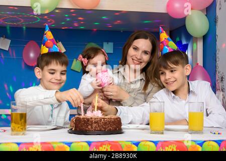 Kinder an einem Familiengeburtstag haben Kerzen in einen Geburtstagskuchen gesteckt Stockfoto
