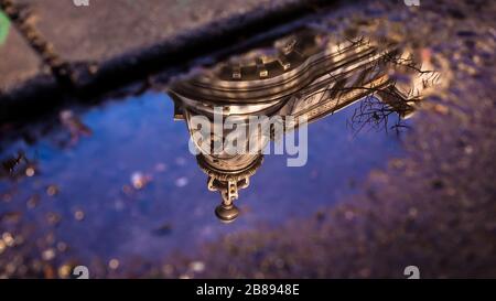 Reflexionen in Pfützen oder am See von Gebäuden, Booten oder Bäumen und Straßenlaternen. Stockfoto