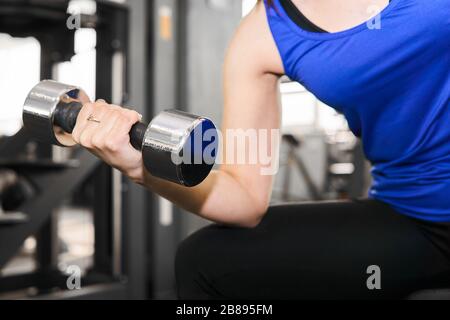 Hand einer Frau, die in der Sporthalle eine Hantelübung für Bizeps durchführt Stockfoto