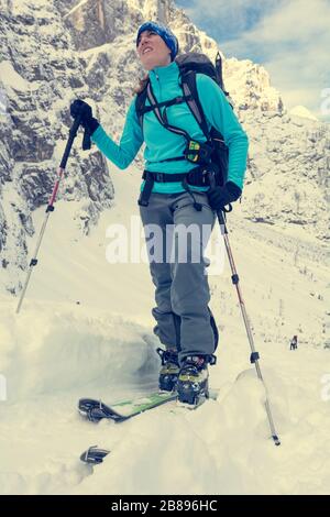 Weiblicher Skitourer mit aufsteigender schneebedeckter Bergabfahrt. Stockfoto