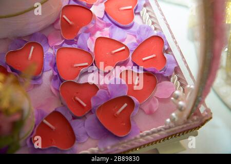 Kerzen in Form von Herzen. Froher Valentinstag. 14. Februar, Frauentag, 8. März. Draufsicht. Flaches Lay. Grußkarte. Herzen auf der rosafarbenen Blütenhülle. Stockfoto