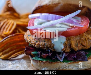 Veganer Kichererbsenburger mit Süßkartoffelchips. Stockfoto