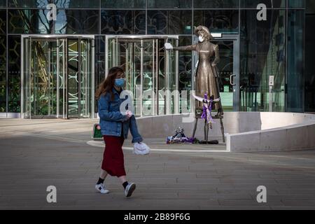 Manchester, Großbritannien. März 2020. Ein Mitglied der Öffentlichkeit, das eine Maske trägt, geht an der politischen Aktivistenstatue von Emmeline Pankhurst vorbei, die die Führerin der Suffragettenbewegung war. Gutschrift: Andy Barton/Alamy Live News Stockfoto