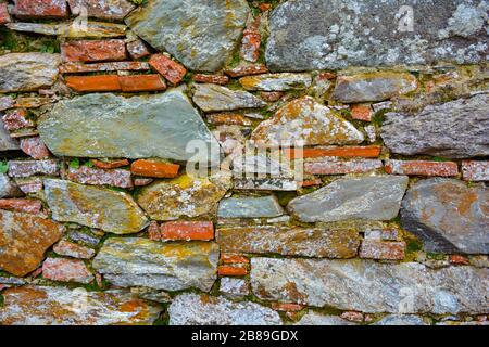 Nahaufnahme einer alten, alten Mauer aus Flusssteinen und Ziegeln. Architektur Hintergrund der regulären Felsen, antike Ziegel, aus einem historischen Gebäude Stockfoto