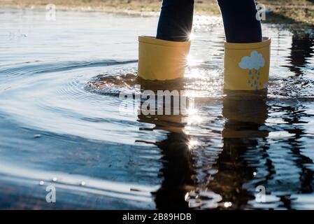 Kinder Regenstiefel in einer großen Wasserpfütze bei Sonnenuntergang Stockfoto