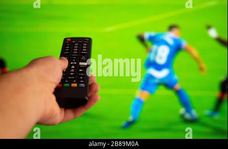 Nehmen Sie mit dem fernseher mit Fußball eine fernbedienung. Fußball- und tv-Konzept. Stockfoto
