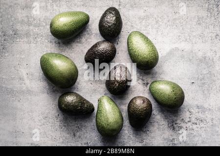 Verschiedene Avocados, die in einer zufälligen Gruppe auf neutralem Hintergrund liegen Stockfoto