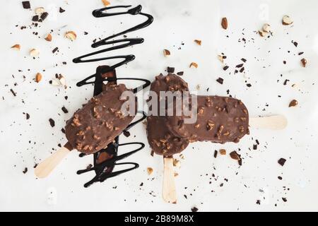 Drei Eisdielen auf weißem Hintergrund, Schokoladenniesel und Nüsse Stockfoto