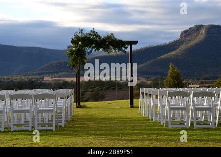 Hochzeitsbogen mit Reihen weißer Stühle bereit für eine Zeremonie mit Blick auf das Hunter Valley in NSW, Australien Stockfoto
