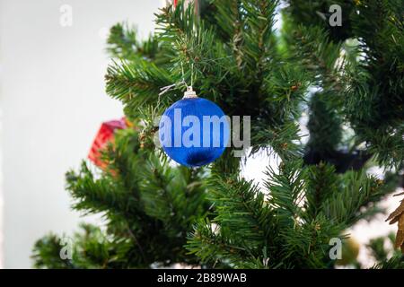 Blauer Weihnachtsball, der an Kiefernzweigen hängt, feiern festlich auf weißem Hintergrund Stockfoto
