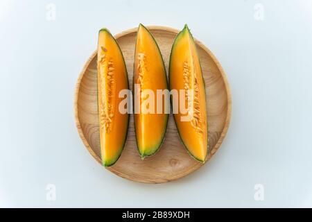 Frische Melonen auf Holzplatte auf weißem Grund geschnitten Stockfoto