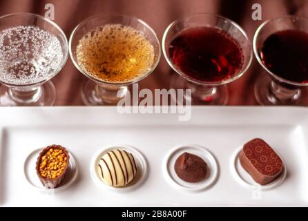 Kleine Geschmäcker verschiedener Weine, von Sekt bis Dessertwein, werden mit ausgefallenen Pralinen serviert Stockfoto