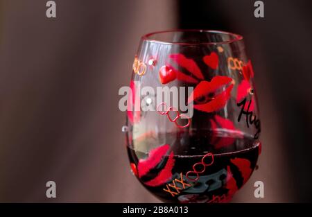 Ein dekoratives, bemaltes Glas hält köstlichen Rotwein Stockfoto