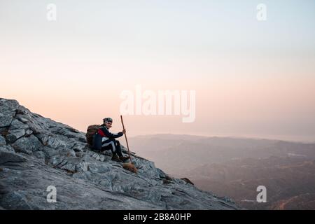 Mann, der auf dem Berg in der Nähe der Klippe wandert. Stockfoto