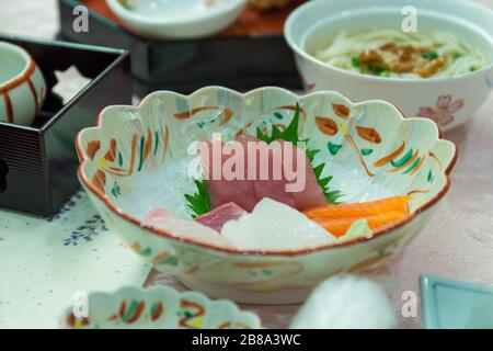 Lachs oder Thunfisch Sashimi auf japanische Gerichte mit Gemüse und Blumen mit Wasabi auf Tisch. Stockfoto