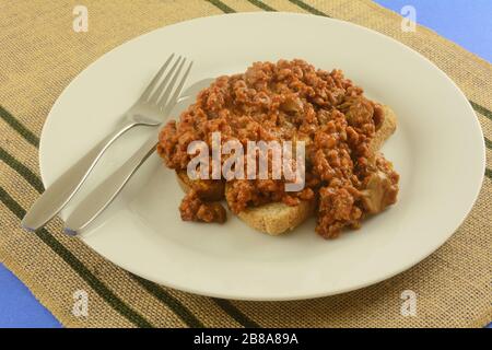 Schlampiger Joe mit Champignons aus Dosen mit Toast auf Phite Platte mit Gabel und Messer mischen Stockfoto