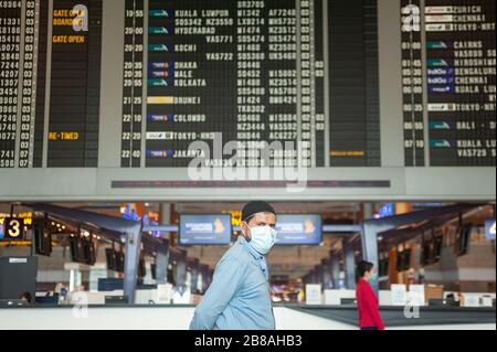 18.03.2020, Singapur, Republik Singapur, Asien - EIN Mann läuft an einer Fluginformationsanzeige in der Abflughalle am Terminal 2 des Flughafens Changi vorbei. Stockfoto