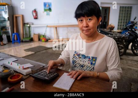 Indonesische Frauen in Asien, die Eigentümerin eines kleinen, örtlichen Familienunternehmens oder lokal Warung genannt werden, berechnen den Gewinn an ihrem Schreibtisch. Selektives Focu Stockfoto