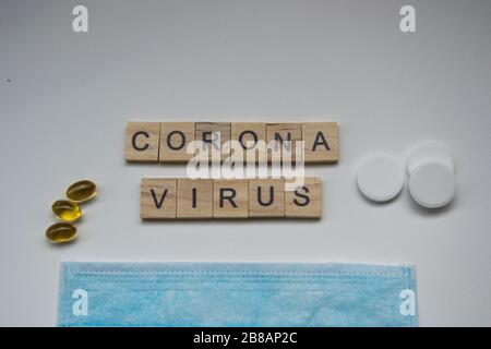 Holzfliesen mit den Buchstaben CORONA-VIRUS auf weißem Hintergrund, Kovid-19, Kronenvirus, Pillen und Maske, Gesundheitskonzept, Pandemie Stockfoto